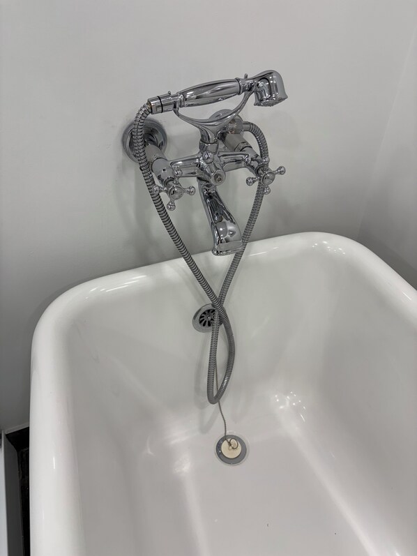 A bathroom with a white bathtub, a chrome faucet, and a showerhead.