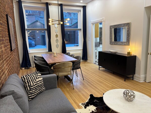 A modern living room with a sofa, a dining table, and a black cabinet.