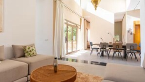 Ein modernes Wohnzimmer mit einer Couch, einem runden Holztisch und einem Essbereich mit Stühlen und Tisch.