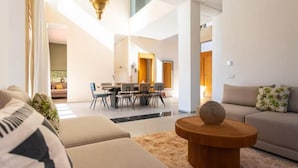 Ein modernes Wohnzimmer mit einer Couch, einem Couchtisch und einem Essbereich mit Stühlen und einem Tisch.