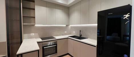 Una cocina moderna con electrodomésticos integrados, una encimera y un refrigerador negro.