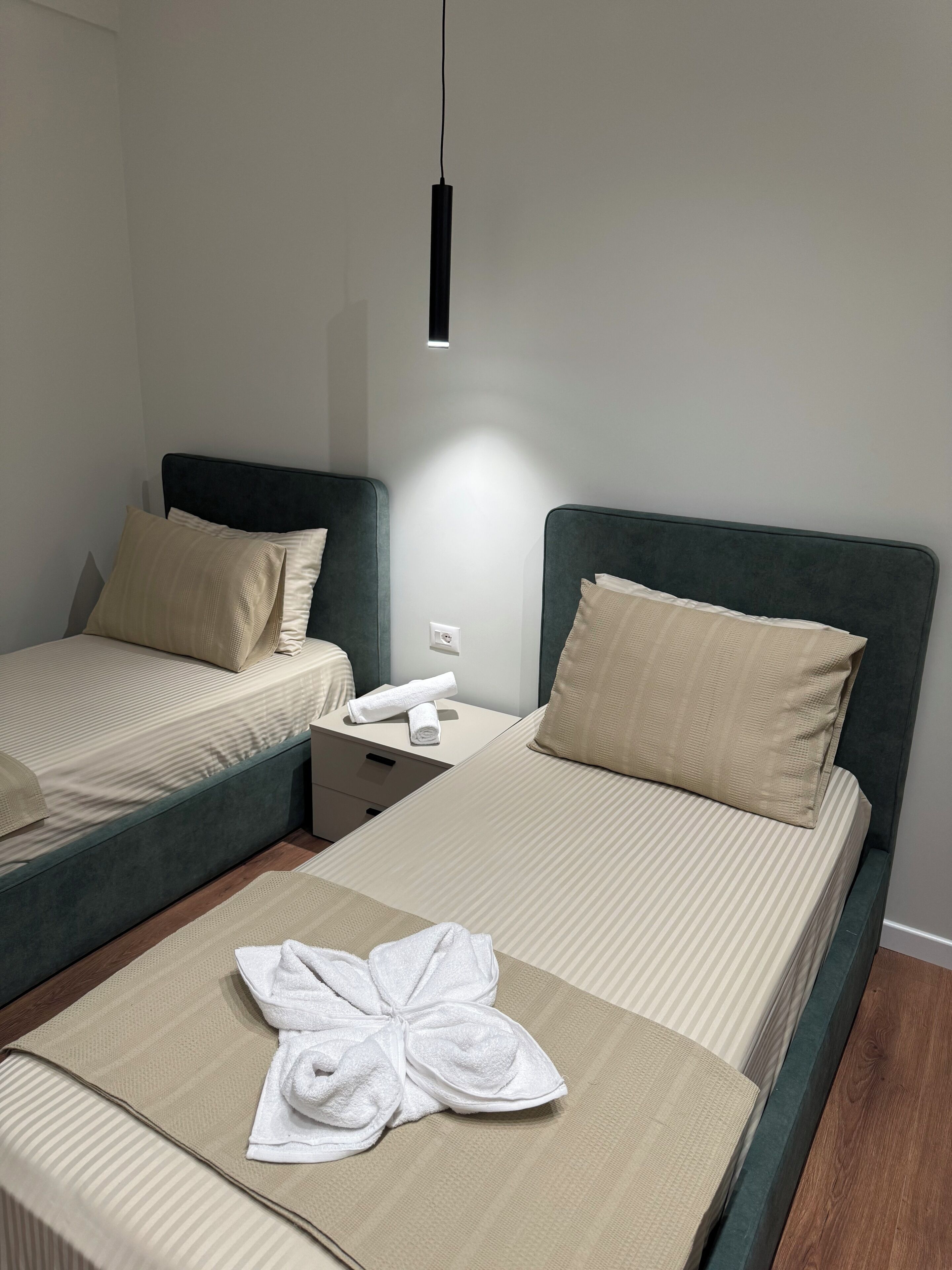 Habitación de hotel con dos camas, una mesita de noche, una lámpara y una toalla sobre la cama.