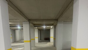 Autotalli, jossa on betonipilarit, lattiaan maalattu suuntanuoli ja kyltti, jossa lukee »DALJE» ja nuoli osoittaa oikealle.