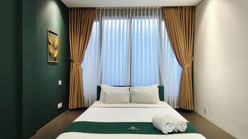 Een hotelkamer met een groot bed, gordijnen en een schilderij aan de muur.