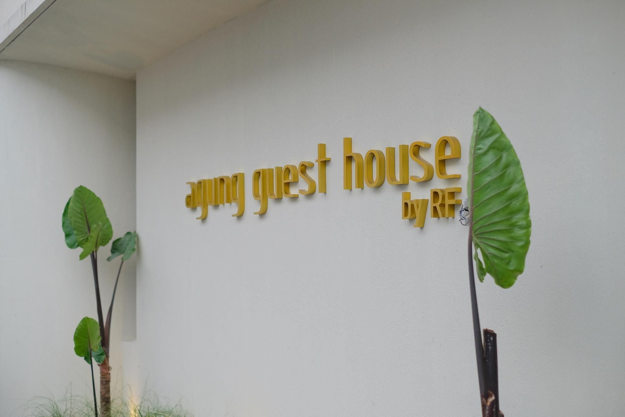 Seinä, jossa on tyylitellyllä fontilla kirjoitettu teksti: ”Ayung Guest House by RF”.