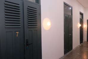 Un couloir avec des portes de couleur sombre, chacune portant un numéro.