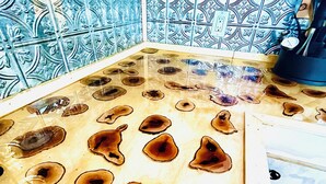 Eine Küche mit einer Holzausziehtheke, die mit kreisförmigen Intarsien verziert ist, und einer gefliesten Spritzschutzwand mit aufwendigen Mustern.