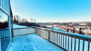 Ein mit Schnee bedeckter Balkon mit Holzgeländer mit Blick auf eine reizvolle Landschaft.
