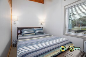 A bedroom with a bed, two wall-mounted lamps, a window with blinds, and a radiator. - Timber Lodge (#235) On ski slope | Triple-decker bunk beds! (Basye)