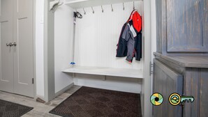 A walk-in closet with a bench, hooks for hanging clothes, and a door. - Lavender Lodge (#237) On ski slope | Triple-decker bunk beds! (Basye)
