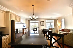 Una cocina amplia con una isla central, un comedor con candelabro y una sala de estar con sofá y lámpara.