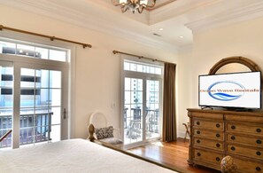 Una habitación de hotel con una cama grande, televisión, cómoda y balcón con vistas a la ciudad.