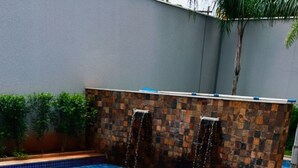 Piscina com um deck ladrilhado e duas espreguiçadeiras.