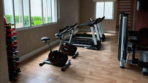 Uma academia com esteiras, uma bicicleta ergométrica e um conjunto de halteres.