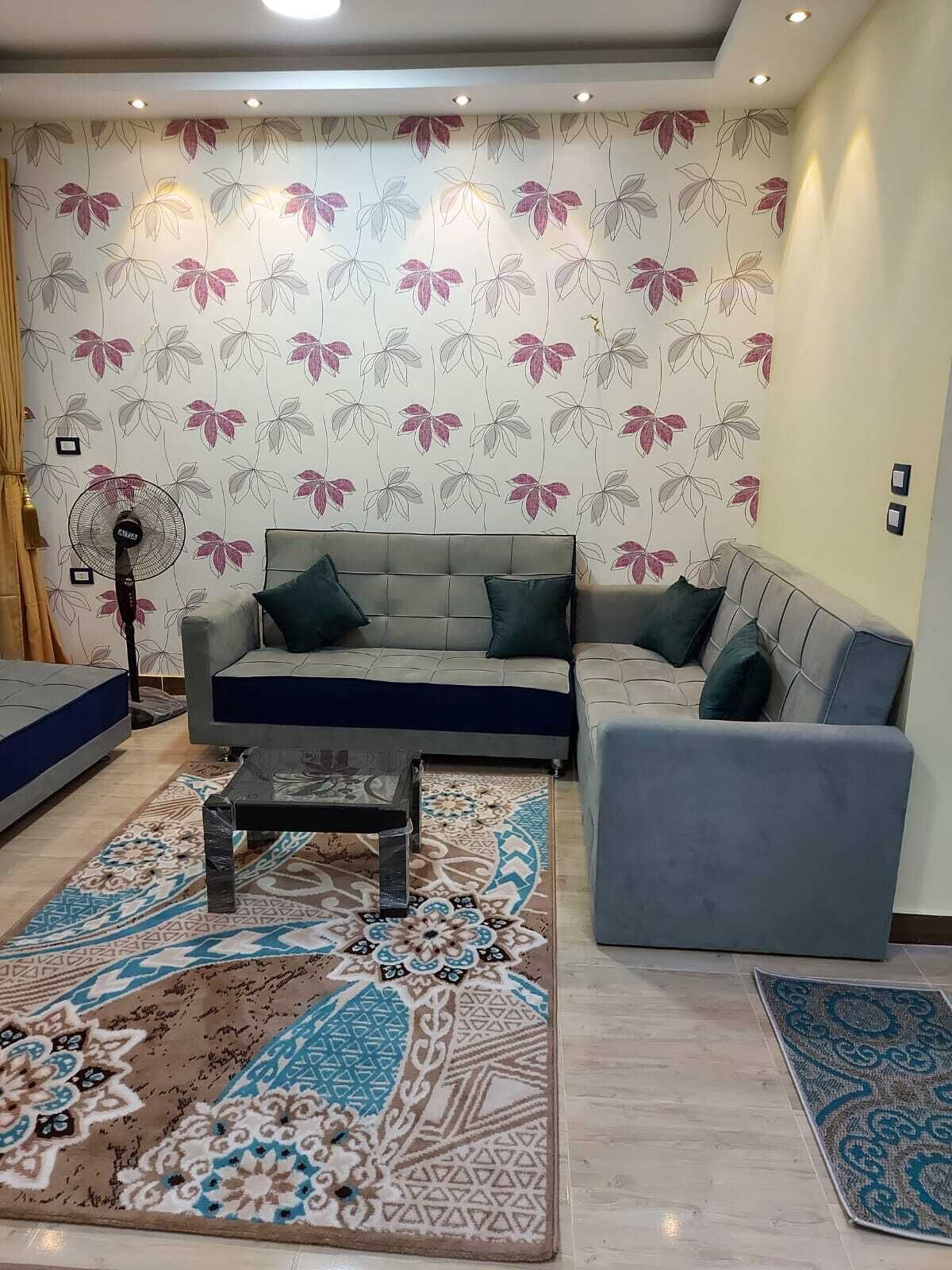 Una sala de estar moderna con un conjunto de sofá, una mesa de centro y alfombras estampadas.