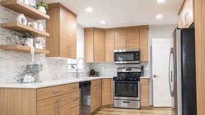A modern kitchen with wooden cabinets, stainless steel appliances, and a tiled backsplash.