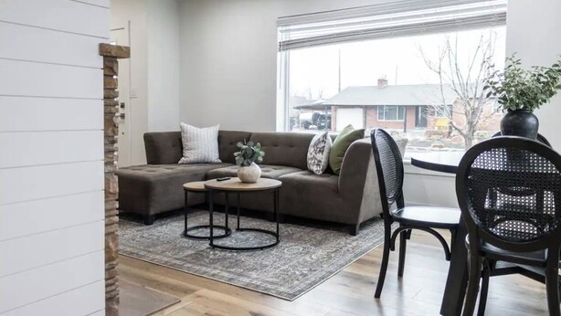 A modern living room with a sectional sofa, a small round table, and a black chair.