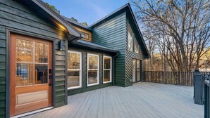 A wooden deck with a house featuring large windows and a garage door.
