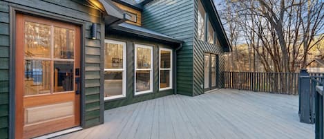 Eine Holzterrasse mit einem Haus, das große Fenster und eine Garagentür hat.