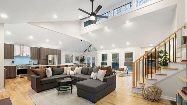 A spacious living area with a sectional sofa, a coffee table, and a staircase leading to an upper level.