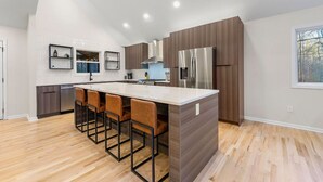 A modern kitchen with a central island, bar stools, and built-in appliances.