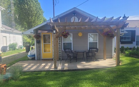 A house with a covered patio, a yellow door, and a small garden area.