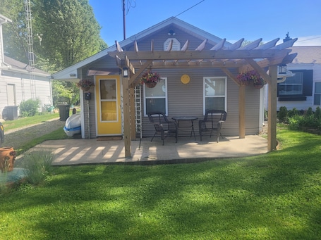 A house with a covered patio, a yellow door, and a small garden area.
