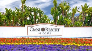 Une enseigne pour l’hôtel Omni Resort, avec un jardin fleuri et coloré en façade.