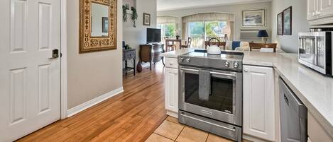 A kitchen with white cabinetry, a stainless steel oven, and a microwave.