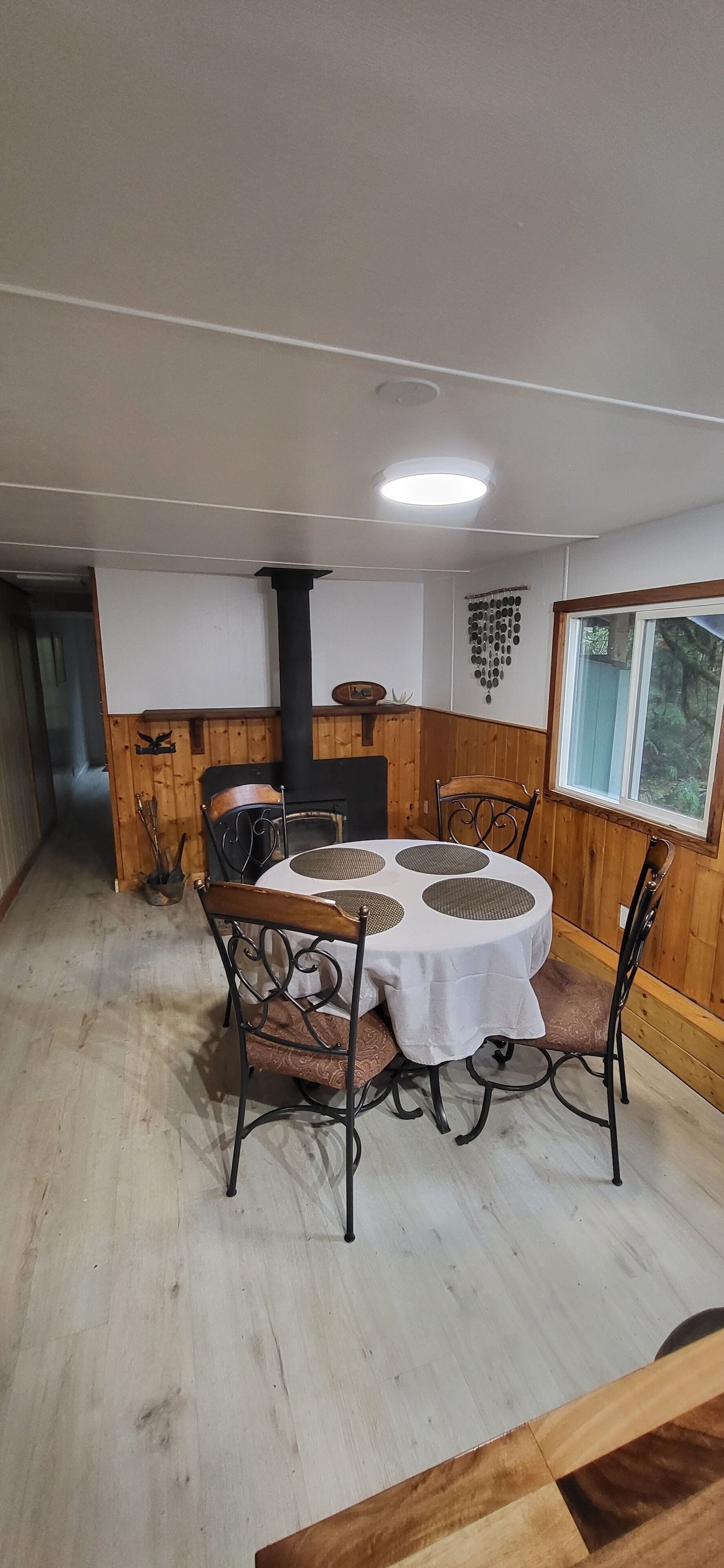 A dining area with a round table, chairs, and a wood-burning stove.