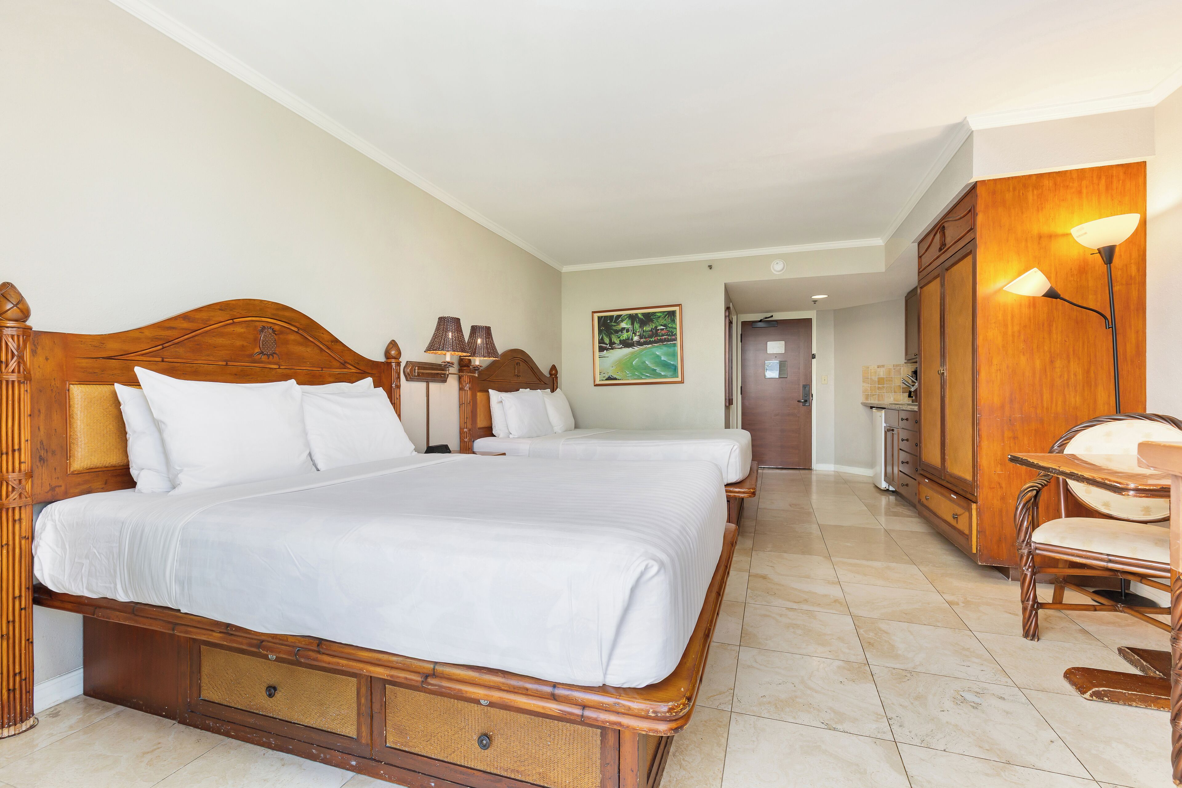 Una habitación de hotel con una cama de madera grande, dos mesitas de noche, un armario de madera y una silla.