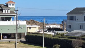 A residential area with a wooden deck, a view of the ocean, and houses with a white picket fence. - OCEANVIEW CONDO:
Outer Banks Oceanside cozy 2-bedroom condo in Kill Devil Hills. (Kill Devil Hills)