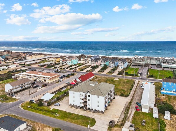 A coastal hotel with multiple buildings, a parking lot, and a view of the ocean.