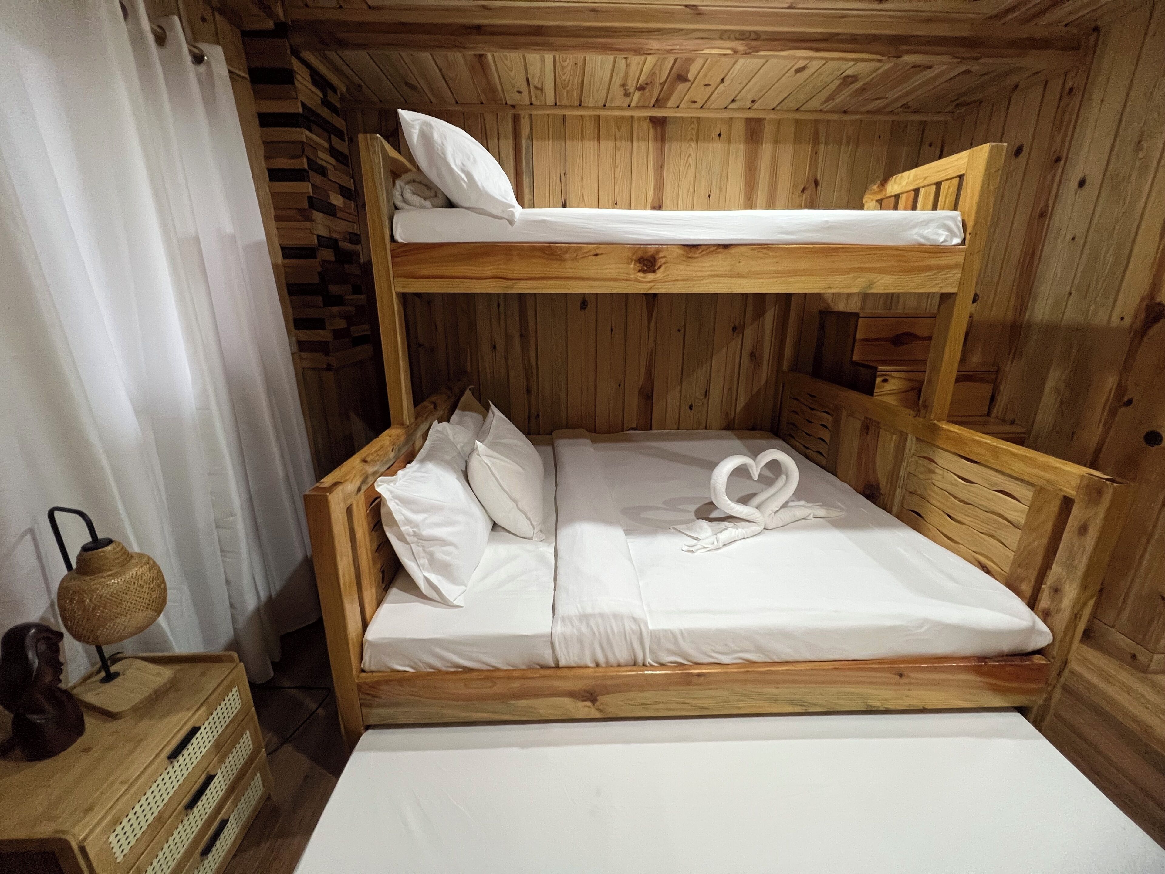 Uma cama beliche de madeira com uma toalha em formato de coração na cama inferior.