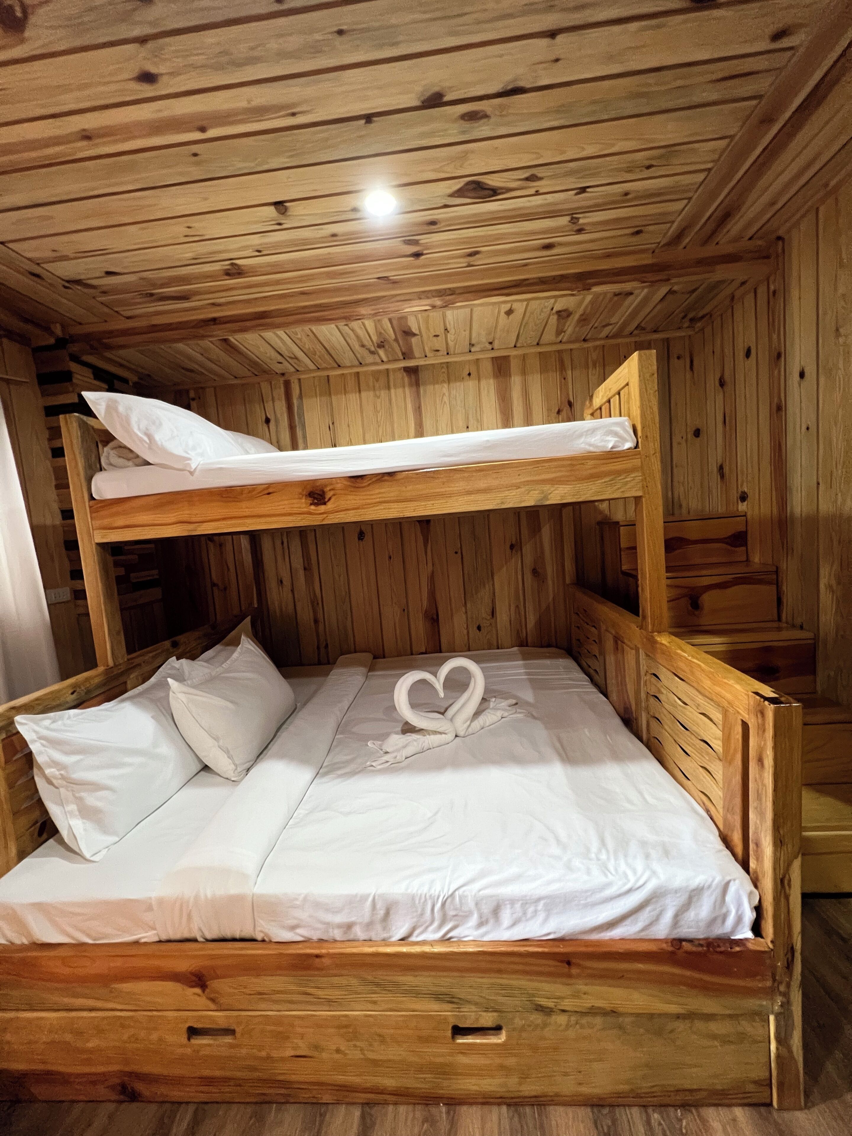A bunk bed with white bedding and a heart-shaped decoration on the lower bed.