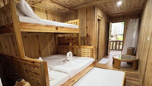 Et træhytteværelse med køjesenge, et lille bord og en flettet kurv.