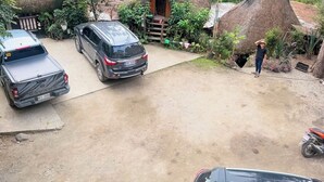 Et idyllisk landskab med bindingsværkshuse med stråtækte tage, en belagt indkørsel og parkerede biler.