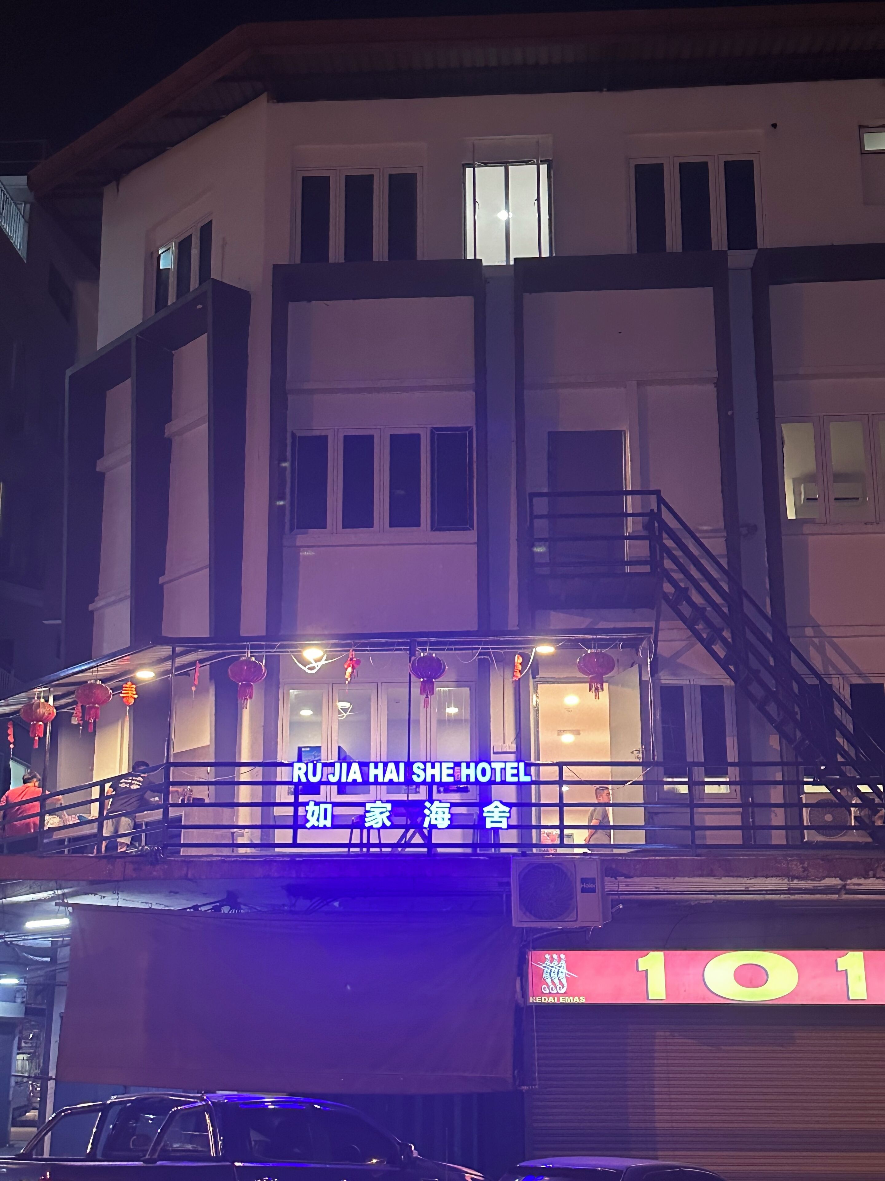 Ein Hotel mit einem Schild, auf dem "Ru Jia Hai She Hotel" steht, und einer sichtbaren Treppe, die zum Eingang führt.