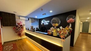 A hotel reception desk with a modern design, featuring a wooden floor and a reception area with a black backdrop. - Ru Jia Hai She Hotel (Semporna)