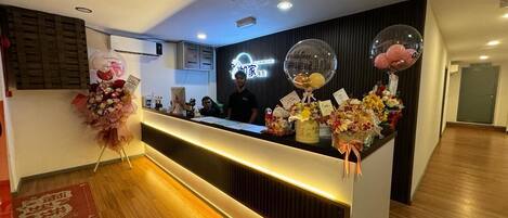 A hotel reception desk with a modern design, featuring a wooden floor and a reception area with a black backdrop.
