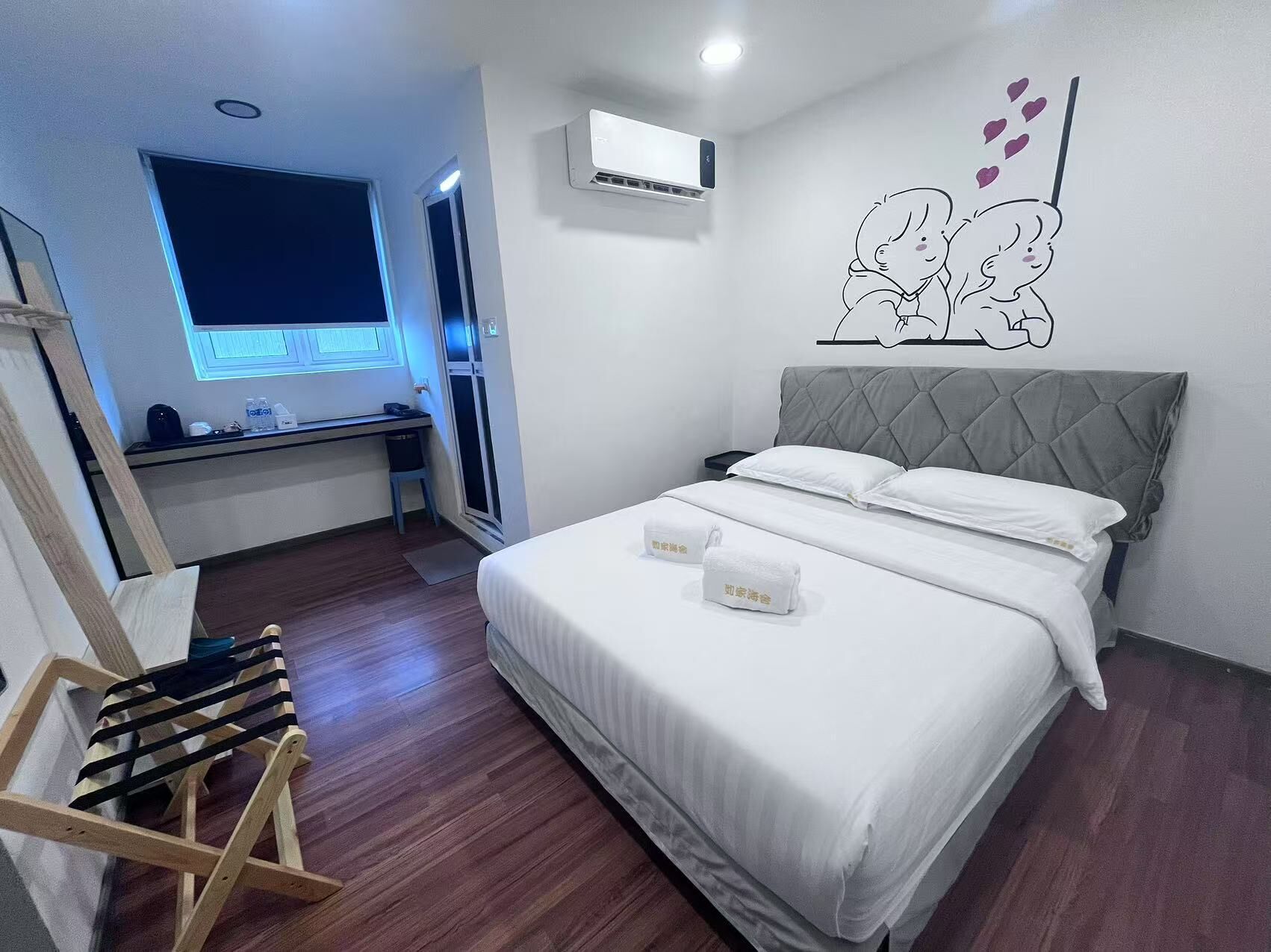 A modern hotel room with a bed, a desk, and a window.