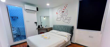 A hotel room with a bed, a bathroom with a shower, a desk, and a large window.