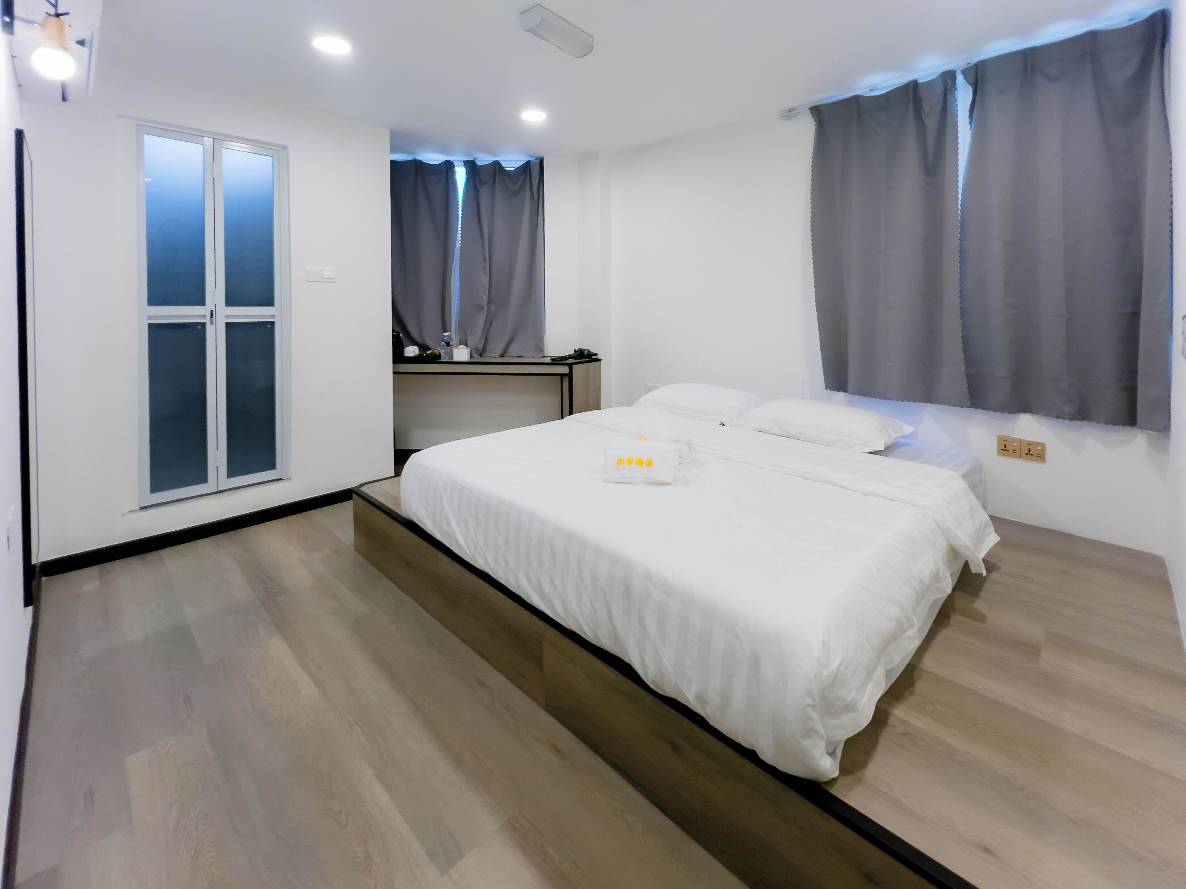 Une chambre à coucher avec un lit, un bureau, une fenêtre avec des rideaux et une porte.