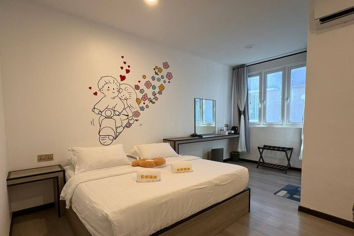 A bedroom with a bed, bedside tables, a desk, and a window.