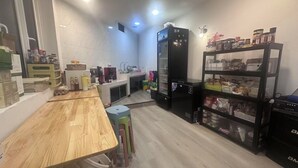 A compact kitchen with a wooden table, a refrigerator, and a shelf with jars. - Ru Jia Hai She Hotel (Semporna)