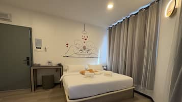 A hotel room with a bed, a desk, a chair, a mirror, and a wall decoration.