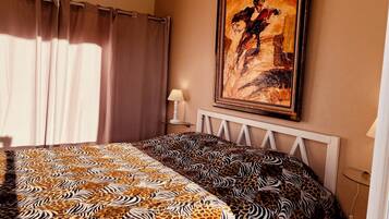 Une chambre à coucher avec une couvre-lit à motifs zébrés, un tableau au mur et une lampe de chevet.