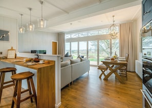 Een moderne keuken met een houten eiland, barkrukken, een bank en een eettafel met stoelen.
