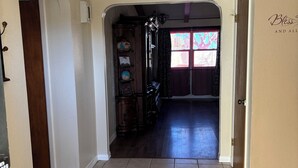 Un pasillo con piso de baldosas, una puerta de madera a la izquierda y otra puerta a la derecha.
