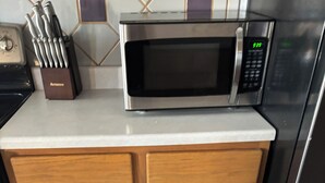 Una cocina con microondas, un cajón con utensilios y una estufa.